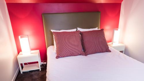 1 dormitorio con paredes rojas y 1 cama con almohadas rojas en Cottage "Les MARAIS" à quelques pas du Lac de la forêt d'Orient - Les Cottages du Belvédère, en Mesnil-Saint-Père