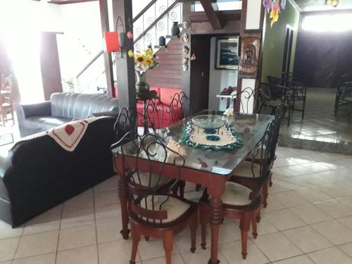 a dining room with a table and chairs and a couch at Pousada Casa D` Guio in Rio das Ostras