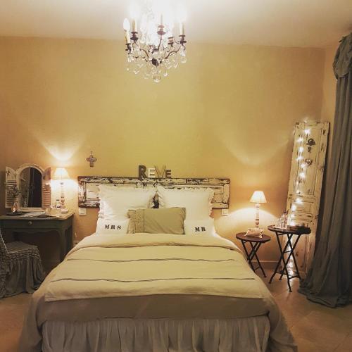 une chambre avec un grand lit et un lustre dans l'établissement Fontaine de Cérier, à Castillon-du-Gard