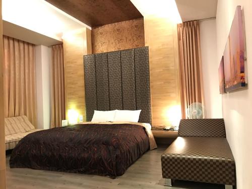 a hotel room with a bed and a chair at Hiye Fashion Motel in Dounan