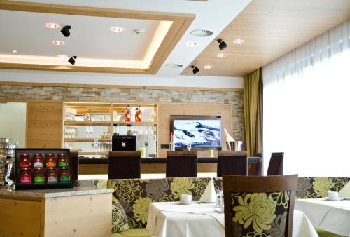 a restaurant with tables and chairs and a television at Hotel Garni Arosa in Ischgl