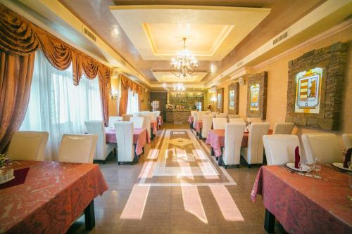 a restaurant with tables and white chairs and a chandelier at База відпочинку ЕЛЬДОРАДО in Solochyn