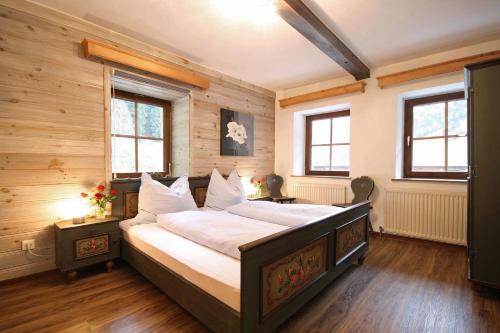 Schlafzimmer mit einem großen Bett mit Holzwänden und Fenstern in der Unterkunft Almliesl MITT-581 in Mittersill