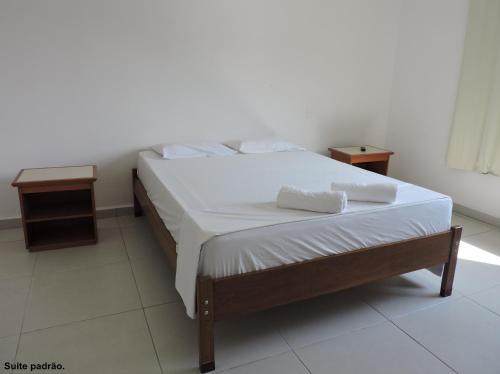 a bed with white sheets and pillows in a room at Consulado Praia Hotel in Guarujá