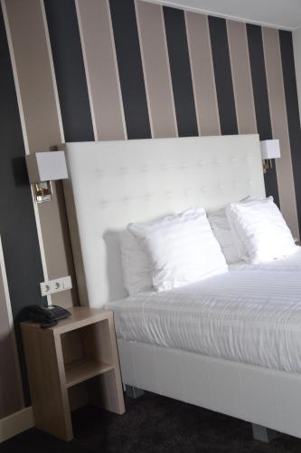 a bedroom with a white bed with a striped wall at Fletcher Hotel-Restaurant Duinzicht in Ouddorp