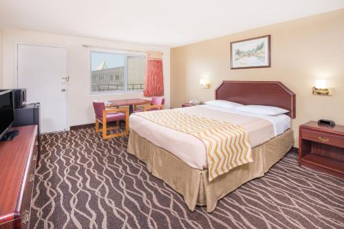 a hotel room with a large bed and a table at Travelodge by Wyndham Terre Haute in Terre Haute