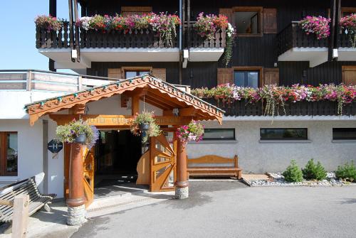 a wooden gazebo in front of a building with flowers at Hotel le Petit Dru in Morzine