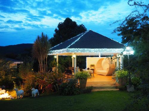 a gazebo with lights in a garden at night at Baan Ing Khao in Pak Chong
