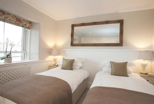 two beds in a bedroom with a mirror on the wall at Victoria House in Stow on the Wold