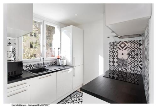 - une cuisine avec des placards blancs et un mur en carrelage dans l'établissement Parc Anahit, à Nice