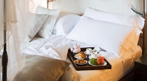 a tray of food on a bed with white pillows at Castello di Gabiano in Gabiano