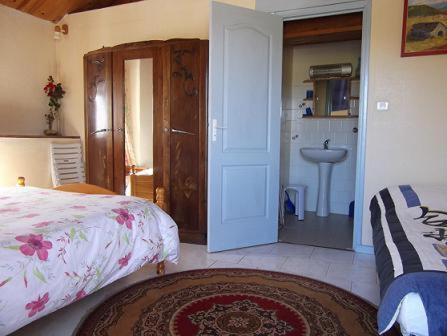 a bedroom with a bed and a bathroom with a sink at Ferme Auberge La Tindelle in La Cresse