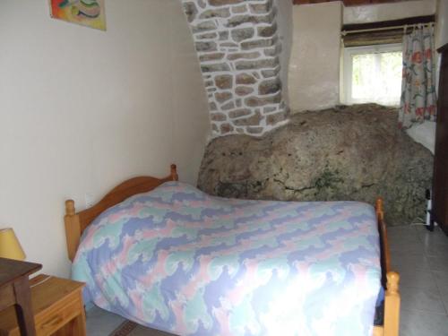 - une chambre avec un lit et un mur en pierre dans l'établissement Ferme Auberge La Tindelle, à La Cresse