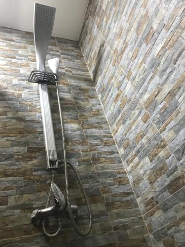 a shower in a bathroom with a brick wall at Prenociste DM5 in Novi Pazar