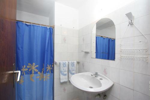 a bathroom with a sink and a blue shower curtain at Complejo Turístico Anaconda Cabañas in La Paloma