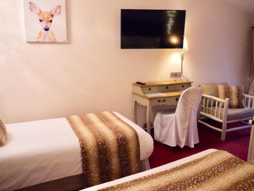 a hotel room with a bed and a desk and a tv at Le Chapeau Rouge in Lusignan