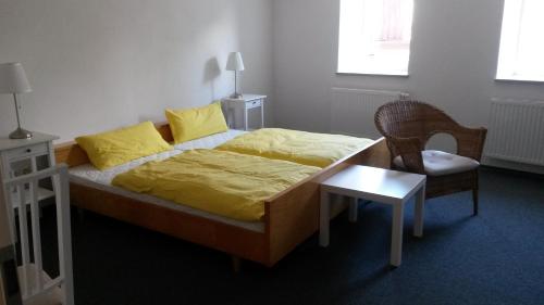 ein Schlafzimmer mit einem Bett mit gelber Bettwäsche und einem Stuhl in der Unterkunft CityZimmer Eltmann in Eltmann