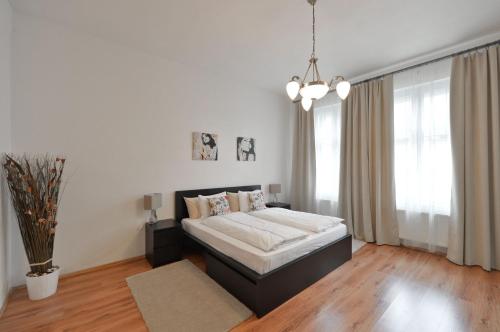 a white bedroom with a bed and a large window at Exclusive apartment on Zborovska in Prague