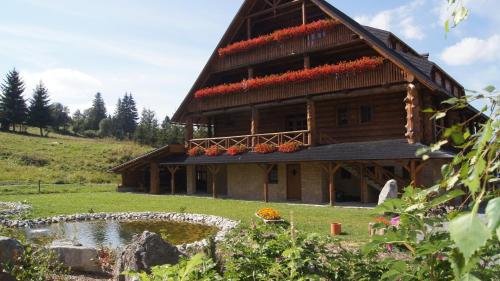 a large wooden house with a pond in front of it at Penzion Pribisko in Zuberec