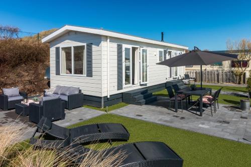 a small white house with chairs and an umbrella at CHALETS IN THE DUNES nearby the beach in IJmuiden