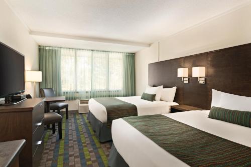 a hotel room with two beds and a flat screen tv at Days Inn by Wyndham Victoria Airport Sidney in Sidney