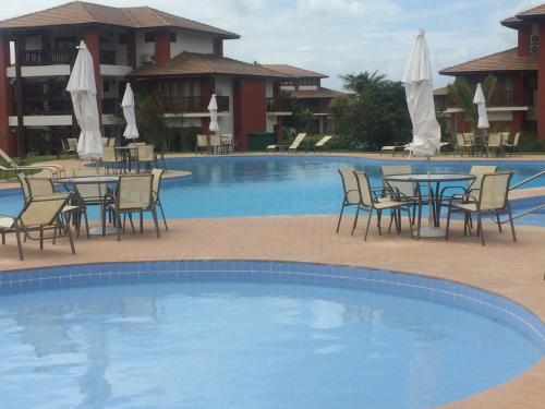 una piscina con mesas y sillas frente a un hotel en village na praia do forte en Praia do Forte