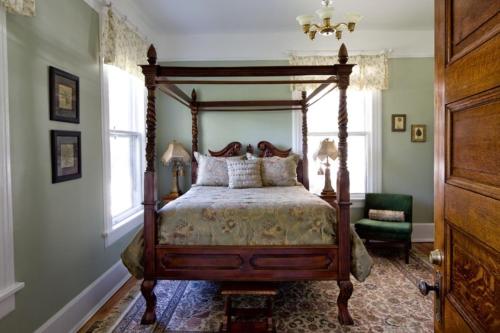 a bedroom with a canopy bed and a chair at Chestnut Street Inn in Asheville