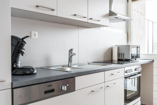a kitchen with white cabinets and a sink at Wohnen auf Zeit - Innenstadt-Appartements in Freiburg im Breisgau