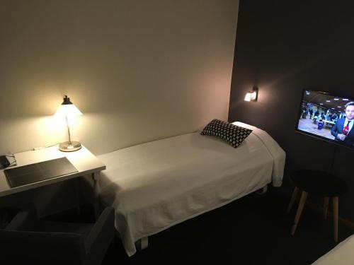 a small room with a bed and a television at Hotel Liselund in Nykøbing Falster