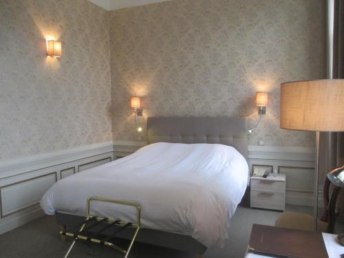 a bedroom with a white bed and two lights on the wall at Château des Monthairons Hôtel Restaurant GastroMaison Spa privatif in Les Monthairons