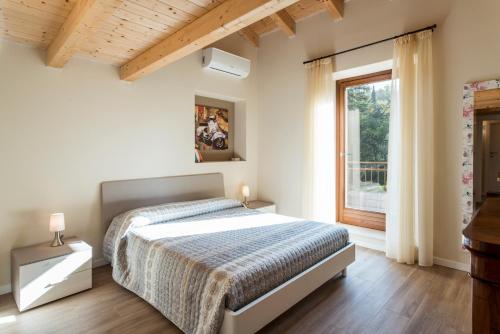 a white bedroom with a bed and a window at Cascina La Scala in Salò
