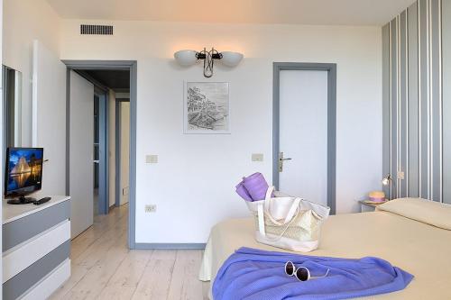 リッチョーネにあるResidence Riccione Beach Apartmentsのベッドルーム(紫のシーツが敷かれたベッド1台、テレビ付)