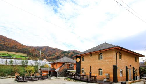 a large brick building with mountains in the background at Daegwanryeong Rodem Tree Pension in Pyeongchang 