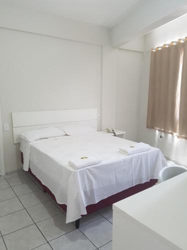 a white room with a bed with white sheets at Leal Classic Hotel in Itabuna