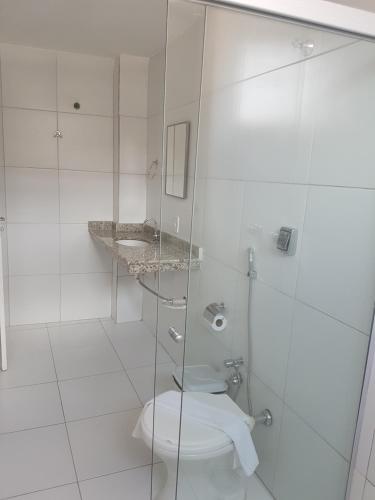 a bathroom with a toilet and a glass shower at Leal Classic Hotel in Itabuna