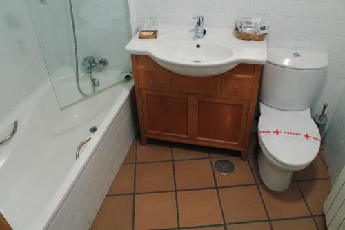 a bathroom with a toilet and a sink and a tub at Hotel Sara De Ur in La Cabrera