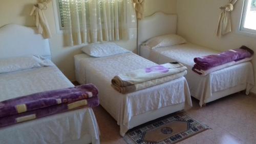 three beds in a room with purple blankets at HoTEL AFOULKI in Tafraout