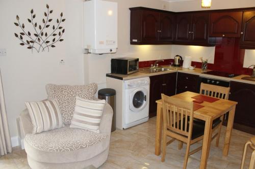 a kitchen with a table and a chair and a kitchen with a washing machine at Wild Atlantic Accommodation 2G Orchard Crescent in Letterkenny