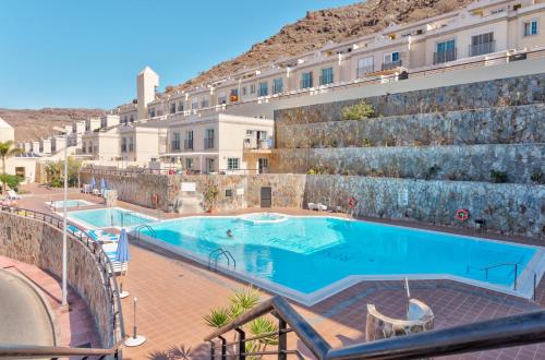 a large swimming pool in front of a building at Apartamento El Valle Puerto Rico con Jacuzzi in Puerto Rico de Gran Canaria