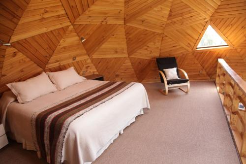 sypialnia w drewnianym domku z łóżkiem i krzesłem w obiekcie Turismo del Bosque w mieście Castro