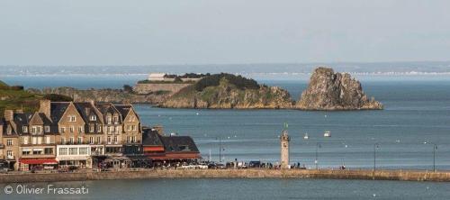 a group of houses and a lighthouse in the water at La Capitainerie in Cancale