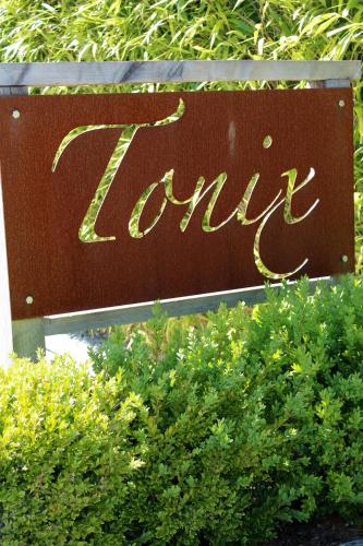 een bord voor een hotel met struiken ervoor bij Tonix Boutique Accommodation in Lawrence