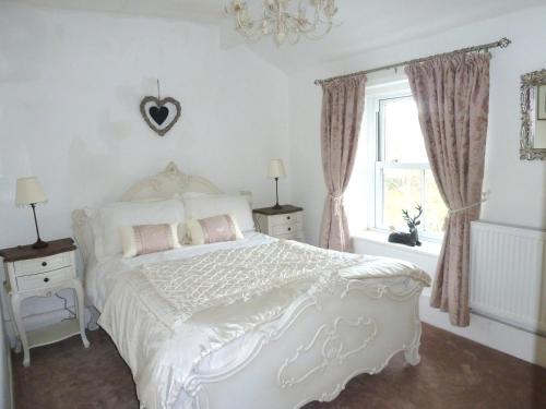 a bedroom with a white bed and a window at Holme House Cottage in Oakworth