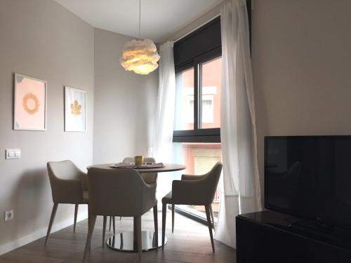 ein Esszimmer mit einem Tisch, Stühlen und einem Fenster in der Unterkunft Unique Apartments in Hospitalet de Llobregat