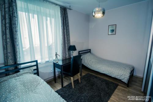 グディニャにあるWrzosowy apartamentのベッドルーム1室(ベッド2台、デスク、窓付)