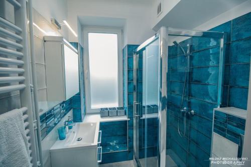 グディニャにあるWrzosowy apartamentの青いバスルーム(シンク、シャワー付)