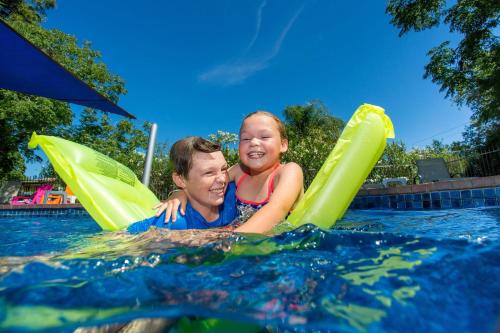 a man and a woman riding on inflatables in a pool at Wodonga Holiday Park in Wodonga