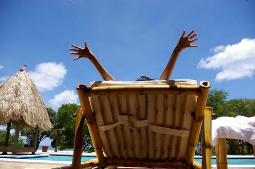 a person sitting in a chair by a pool at Punta Teonoste Beach Resort in Popoyo