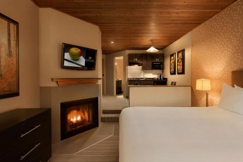 1 dormitorio con 1 cama y chimenea en Executive Inn Whistler, en Whistler