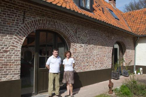 a man and woman standing in front of a brick building at B&B - La Cense du Pont in Bachy